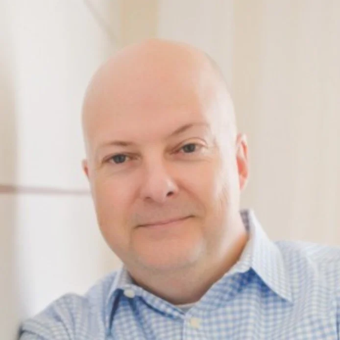 Smiling man in a blue checkered shirt.